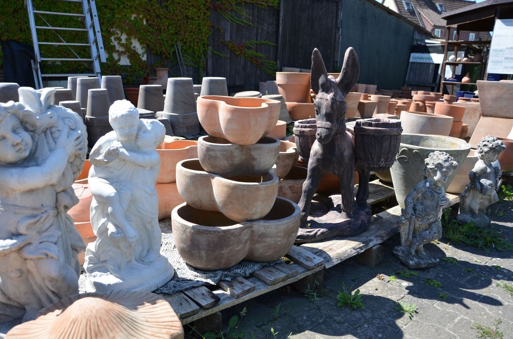 Sammlung von Pflanzentöpfen und Gartenfiguren im Außenbereich